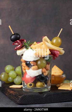 Jarcuterie en verre comprend divers types de saucisses, de cornichons, de fromage, de noix, de légumes et de fruits. Version moderne d'en-cas festifs Banque D'Images