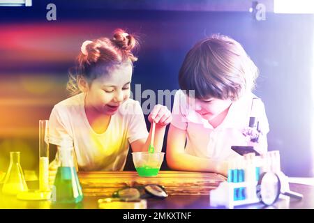 Enfants scientifiques. Les écoliers en laboratoire mènent des expériences. Garçon et fille expérimente avec un microscope. Banque D'Images