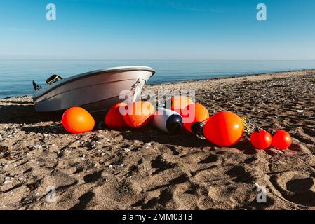 Bouées orange et bateau de pêche argenté sur une plage de sable sur la rive de la mer de Kattegatt au soleil, Djursland, Jutland, Danemark Banque D'Images