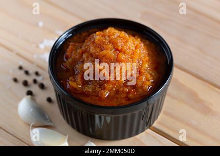 Sauce adjika maison dans un bol en gros plan, sur une table en bois Banque D'Images