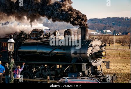 Ronks, Pennsylvanie, 28 décembre 2022 - Vue sur un train de passagers à vapeur classique qui s'approche, se déplace à travers la campagne, souffle de fumée et de vapeur lors d'une journée d'hiver Banque D'Images