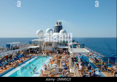 Bateau de croisière en mer, avec de nombreux vacanciers à la piscine. Banque D'Images