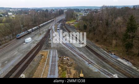 Vue aérienne d'un chemin de fer de fret de triage de fret en construction, avec un train de voyageurs passant Banque D'Images