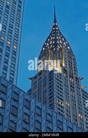 Vue d'avant l'aube du Chrysler Building, un monument historique de la ville de New York, entouré d'un bâtiment Socony-Mobil en acier inoxydable. Banque D'Images