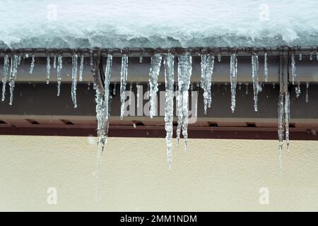 Il y a beaucoup de glaces suspendues au bord du toit, en hiver Banque D'Images