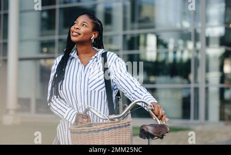 Une jeune femme aspirant rêve de son succès tout en se déplaçant avec un vélo dans la ville. Jeune femme d'affaires pensive qui se rend au travail dans la ville Banque D'Images