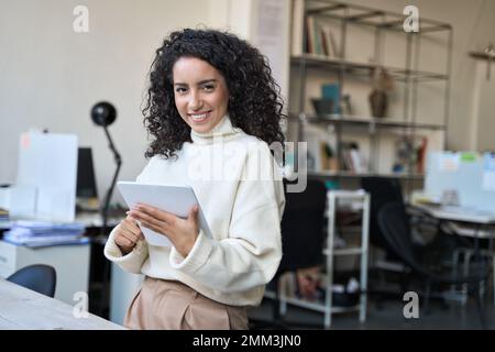 Jeune femme d'affaires latine souriante utilisant une tablette numérique au bureau. Banque D'Images