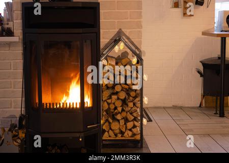 Poêle en métal noir cheminée avec bois dans une pile de bois - l'intérieur d'une maison de village privée. Chauffage et chauffage de la maison avec bois de chauffage, l'hea Banque D'Images