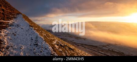 En regardant le dernier sentier enneigé vers le sommet de la montagne Pen-y-ghent au lever du soleil avec la brume et la neige dans le parc national de Yorkshire Dales, en Angleterre Banque D'Images