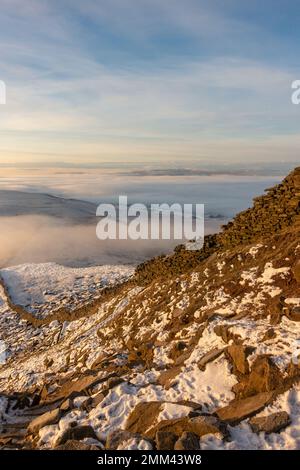 En regardant le mur de pierre vers le chemin final jusqu'au sommet de la montagne Pen-y-ghent au lever du soleil avec la brume et la neige dans le Yorkshire Dales NAT Banque D'Images