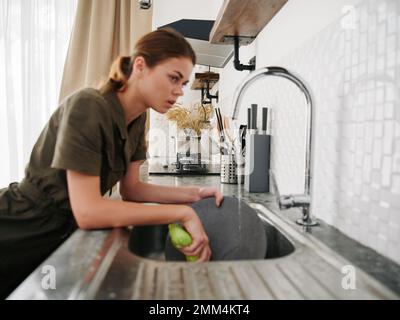 Femme fatiguée et fâchée mains sans gants lave la vaisselle avec une éponge de lave-vaisselle avec des bulles, des tâches ménagères, pas de lave-vaisselle, de l'eau élevée Banque D'Images