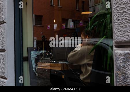Milan, Italie - Otobre 16, 2022: Vue par fenêtre de la jeune femme utilisant son ordinateur portable dans la cafétéria Banque D'Images