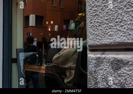 Milan, Italie - Otobre 16, 2022: Vue par fenêtre de la jeune femme utilisant son ordinateur portable dans la cafétéria Banque D'Images