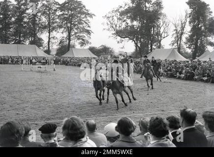 1960s, historique, regardé par des spectateurs, des jeunes sur des chevaux en bordure d'un champ, lors d'un spectacle équestre, qui s'est tenu au parc des expositions de la Société agricole de Didsbury, près de Manchester, Angleterre, Royaume-Uni. Principalement pour les juniors, le spectacle a commencé en 1963 comme un événement local, le Didsbury Light Horse Show et a toujours lieu à Didsbury aujourd'hui, Banque D'Images