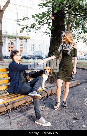 un homme avec un beagle accueille une jeune blonde dans le parc Banque D'Images