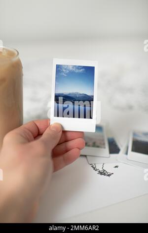 Main tenant Polaroid photo de la montagne sur la carte du monde avec le café glacé Banque D'Images