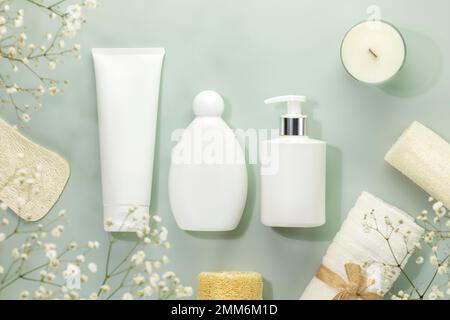 Spa écologique composition détente avec maquette de produits de beauté, bougie et accessoires spa sur fond bleu avec fleurs blanches. Bien-être et peau Banque D'Images