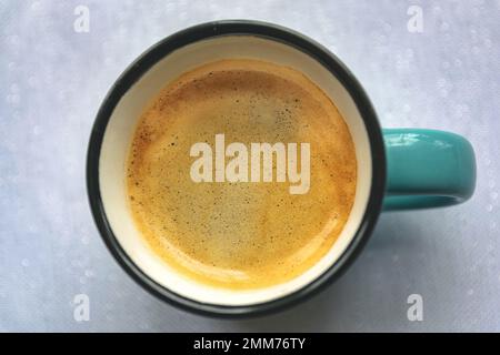 Une petite tasse de café fraîchement préparé avec une bonne couche de crème sur le dessus et un fond blanc éclatant Banque D'Images