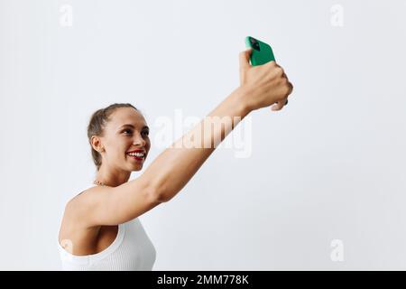 Une femme modèle avec belle peau bronzée se tire sur son téléphone dans des vêtements simples et stylés souriant et posant magnifiquement le contenu de prise de vue et Banque D'Images