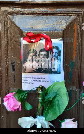 Le jour de la commémoration de l'Holocauste 2023, une main anonyme a épinglé la photo de trois enfants et quelques fleurs sur la vieille porte, au numéro 5999 de Cannaregio, à Venise. Les enfants ont été déportés à Auschwitz, avec leurs parents et leur frère d'un an, en 1943. Ils avaient 14, 10, 7 ans. Ils ont été tués à Auschwitz, sur 26 février 1944, avec leur frère d'un an. Il y a quelques années, 7 « pierres à ventre plat » ont été placées à l'entrée de leur maison. Une note sous la photo dit: ' Anna, Guido, et Giorgia Dina. Le Leone avait un an, et nous ne saurons jamais quel visage il avait". Banque D'Images