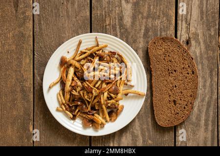 champignons au miel frits sur une assiette avec un morceau de pain noir sur une ancienne table en bois, champignons frits à la maison, déjeuner Banque D'Images