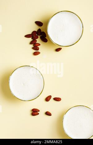 Trois verres de lait d'amande vegan sur fond jaune. Banque D'Images