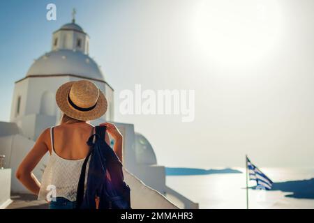 Femme touriste appréciant le paysage de la mer de Caldera à Fira, l'île de Santorini à pied par l'église blanche traditionnelle. Banque D'Images