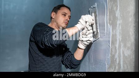 l'homme applique l'isolation à un mur de salle de bains Banque D'Images