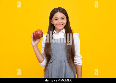 Enfant adolescent avec pomme sur fond jaune isolé. Les pommes sont bonnes pour les enfants. Visage de fille heureux, émotions positives et souriantes. Banque D'Images