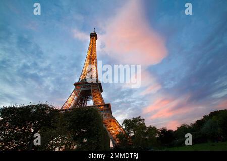 Les lumières s'allument dans la Tour Eiffel tandis que le soleil s'estompe sous l'horizon. Banque D'Images