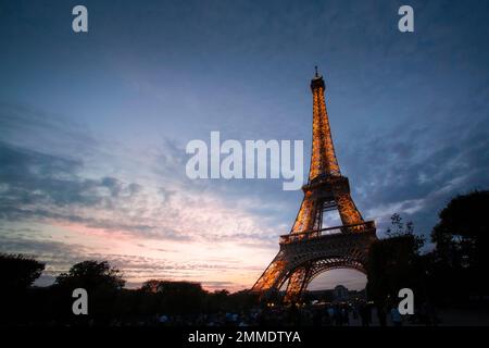 Les lumières s'allument dans la Tour Eiffel tandis que le soleil s'estompe sous l'horizon. Banque D'Images