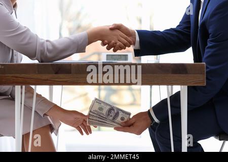 Homme secouant la main de la femme et donnant de l'argent de pot-de-vin sous la table, clôture Banque D'Images