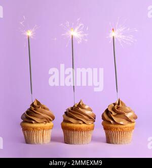 Cupcakes d'anniversaire avec sparkers sur fond violet Banque D'Images