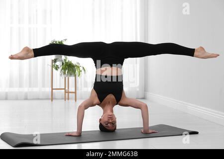 Professionnel jeune acrobat pratiquant le yoga à la maison Banque D'Images