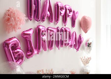 Expression JOYEUX ANNIVERSAIRE fait de lettres de ballons roses dans la chambre décorée Banque D'Images