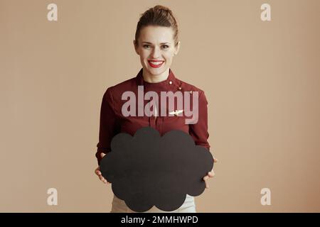 élégante hôtesse féminine souriante isolée sur fond beige et tableau noir en forme de nuage. Banque D'Images