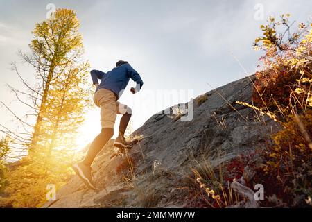 Le coureur monte en amont dans la forêt et les montagnes au coucher du soleil Banque D'Images