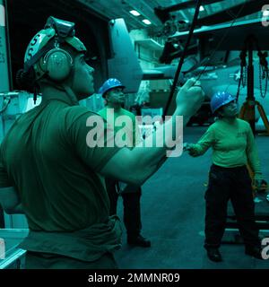 Sergent du corps des Marines des États-Unis Ryan Bobbitt, à gauche, un siège d'éjection et mécanicien de systèmes environnementaux avec Marine Medium Tiltrotor Squadron 262 (rein.), 31st Marine Expeditionary Unit, US Navy aviation machiniste mate troisième classe Jose Jabat, au centre, Et Melanie O. Moody, un compagnon de machiniste de l'aviation de première classe, tous deux avec le navire d'assaut amphibie USS Tripoli (LHA 7), gère une grue pendant l'entretien d'un F-35B Lightning II à bord de Tripoli, dans la mer des Philippines, le 21 septembre 2022. Les agents d’entretien du F-35B, appuyés par des marins qui utilisent une grue pour le levage, effectuent régulièrement l’entretien pour assurer celui de l’avion Banque D'Images