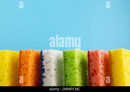 Éponges colorées pour le nettoyage ménager. Éponge pour lave-vaisselle de cuisine sur fond bleu. Concept de ménage. Espace pour le texte. Banque D'Images
