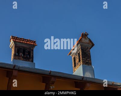 Toit en céramique avec cheminée et mur blanc, ciel bleu comme arrière-plan. Banque D'Images