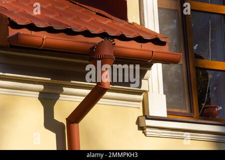 Le toit de la maison est fait de carreaux de métal rouge, une belle grande cheminée. Banque D'Images