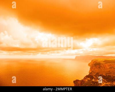 Vue aérienne coucher de soleil rouge sur la mer avec falaise volcanique rocheuse. Résumé nature été coucher de soleil océan mer fond. Petites vagues sur doré chaud Banque D'Images