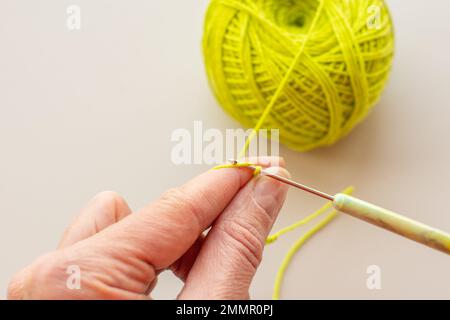 Mains crochetées en coton et crochet sur fond clair, mise au point sélective, avec espace de copie. Tricots écologiques, passe-temps, loisirs, fabrication artisanale Banque D'Images