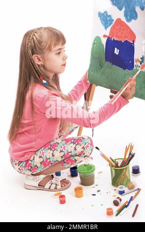 L'enfant dessine une maison. Peinture pour enfants. Petite fille tire le soleil. L'élève fait ses devoirs à l'art. Arts et artisanat pour les enfants. Peinture Banque D'Images