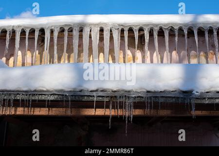 Très belles glaces suspendues dans deux rangées du toit d'une vieille maison. Les glaces pendent du toit comme des stagnation. De longues glaces transparentes pendent Banque D'Images