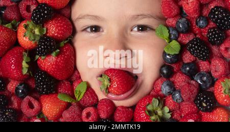 Une alimentation saine pour les enfants. Baies avec enfants face à gros plan. Vue de dessus du visage d'enfant avec berri. Ensemble de baies près du visage des enfants. Un petit garçon mignon mange Banque D'Images