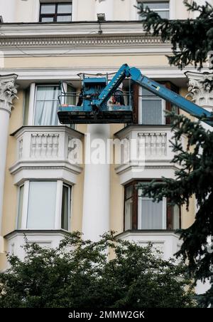 Homme dans le berceau, restauration de la décoration en plâtre sur la façade. Banque D'Images