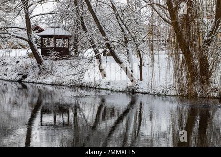 Un petit belvédère en bois dans les profondeurs d'une forêt d'hiver près d'un ruisseau de montagne froid et noyés marchent le long de lui, grimpant d'une vallée forestière. Banque D'Images