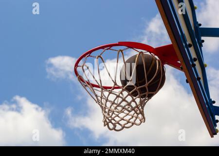 Un basket-ball dans le filet.La boule de commande est dans l'anneau.Un jeu sportif.Conceptuel : victoire, succès, atteinte de la cible, sport.Lancer de balle réussi. Banque D'Images