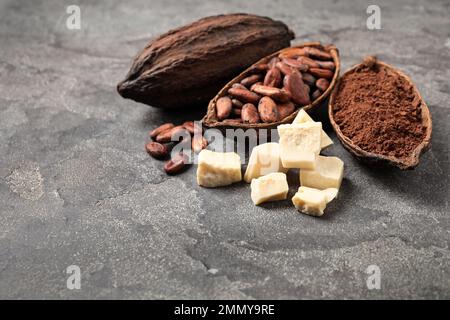 Beurre de cacao biologique, haricots et poudre sur table grise Banque D'Images